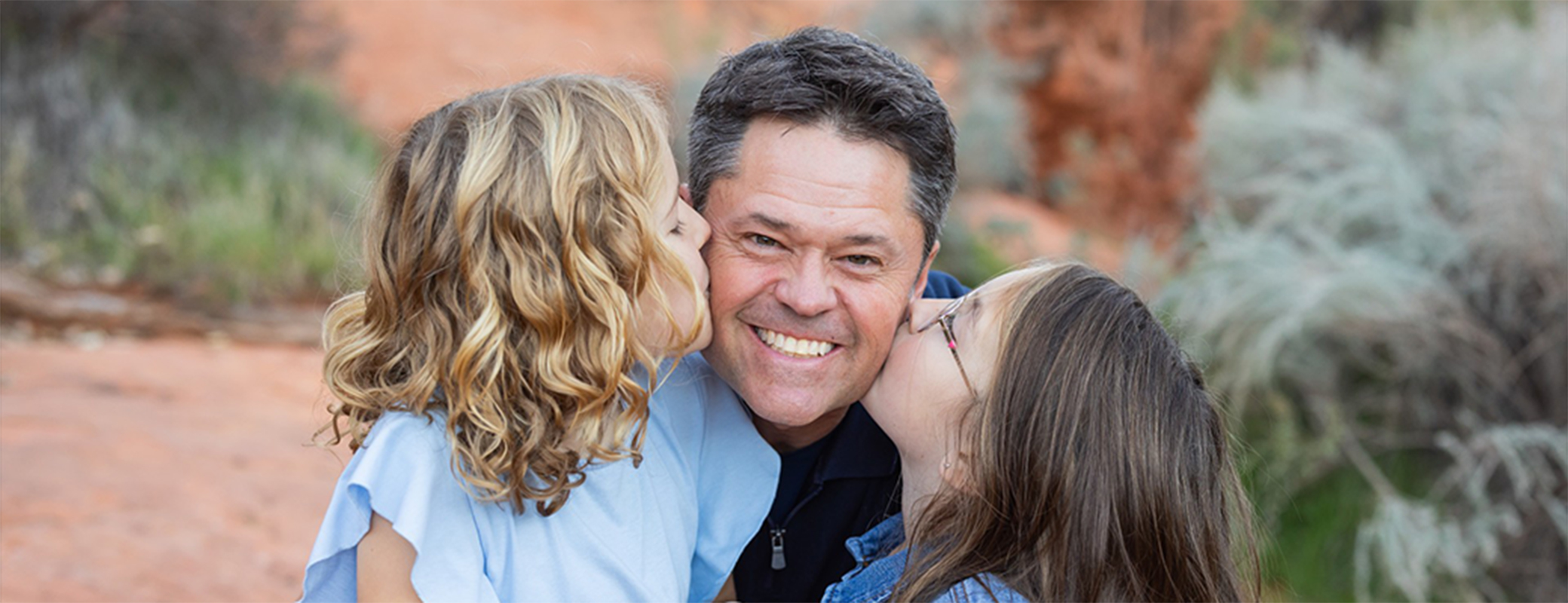 Image of Justin Osmond and his two daughters kissing him on each cheek